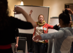 A young white woman leads a group in a choreographed dance exercise.