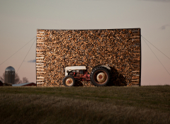 An art installation featuring a tractor and bundles of wood