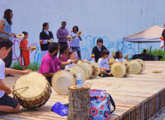 A group of people playing the drums while sitting cross-legged