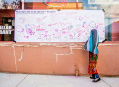 A young girl in a headscarf by a poster that says Whats Special About Cedarside