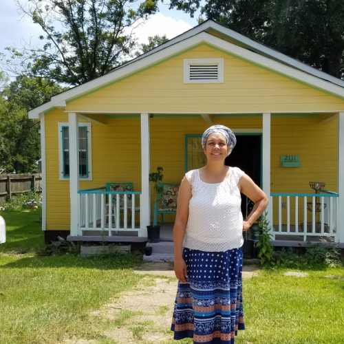 Nia Umoja of the Cooperative Community of New West Jackson standing in front of a yellow  house