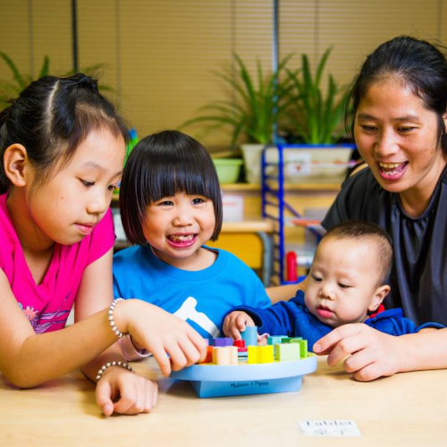 A mother with three children playing with an educational toy