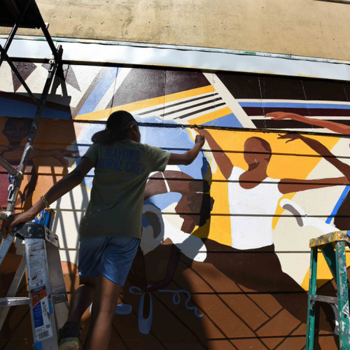Image of an artists painting a wall mural.