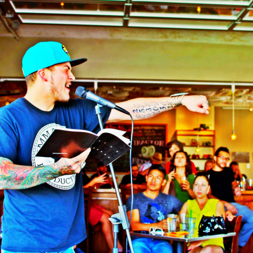 Carlos Contreras by microphone reading spoken word poetry.