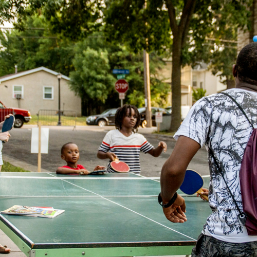A young white woman and a young black man play ping pong