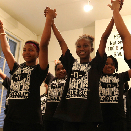 Project Heal Girls - Four young black girls holding hands and smiling at the camera.