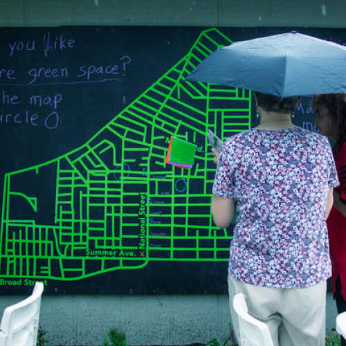 Two people with an umbrella viewing a schematic 