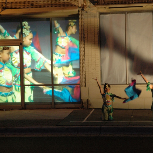 two dancers on the streets with dancers projected in the background