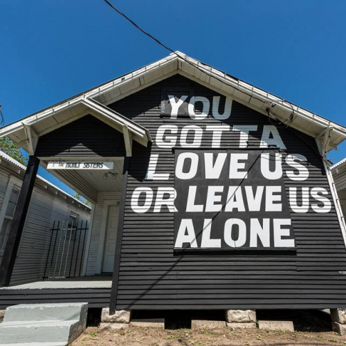 A house painted black with the words "You gotta love us or leave us alone" on it