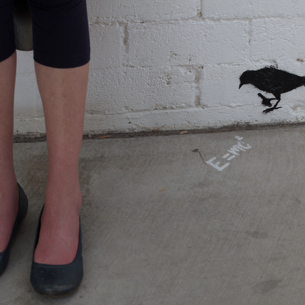 A white woman's legs next two a graffiti image of a bird