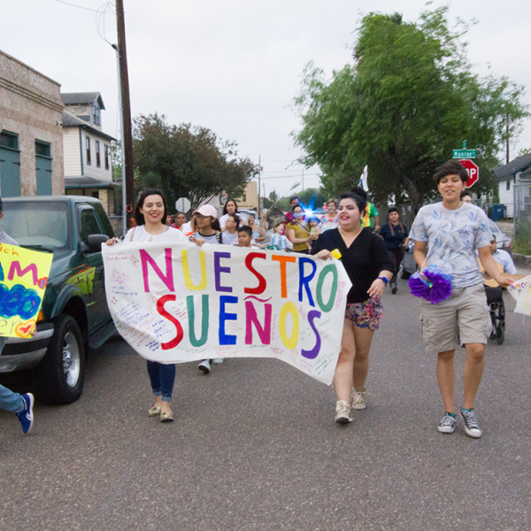 A group of young people of different ethnicities marching with a sign that says "Nuestros Suenos" or Our Dreams