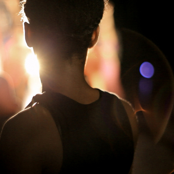 Photo of a young dancer taken of the back of their head as they are illuminated by the light.