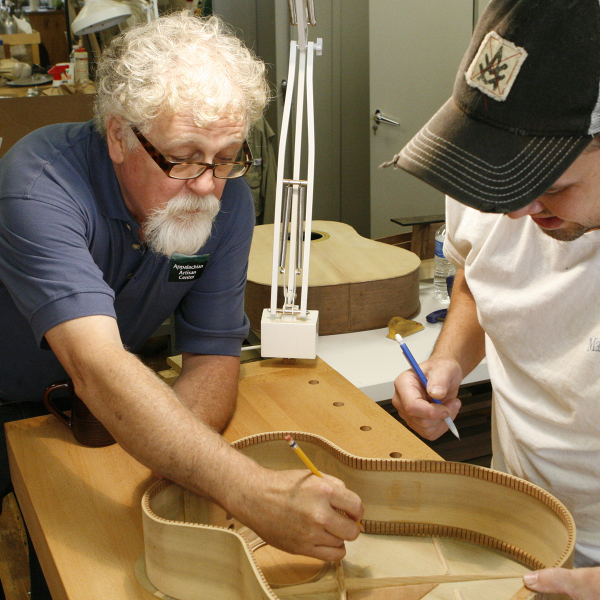 Two artists working on building a guitar.