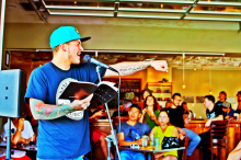 Carlos Contreras by microphone reading spoken word poetry.