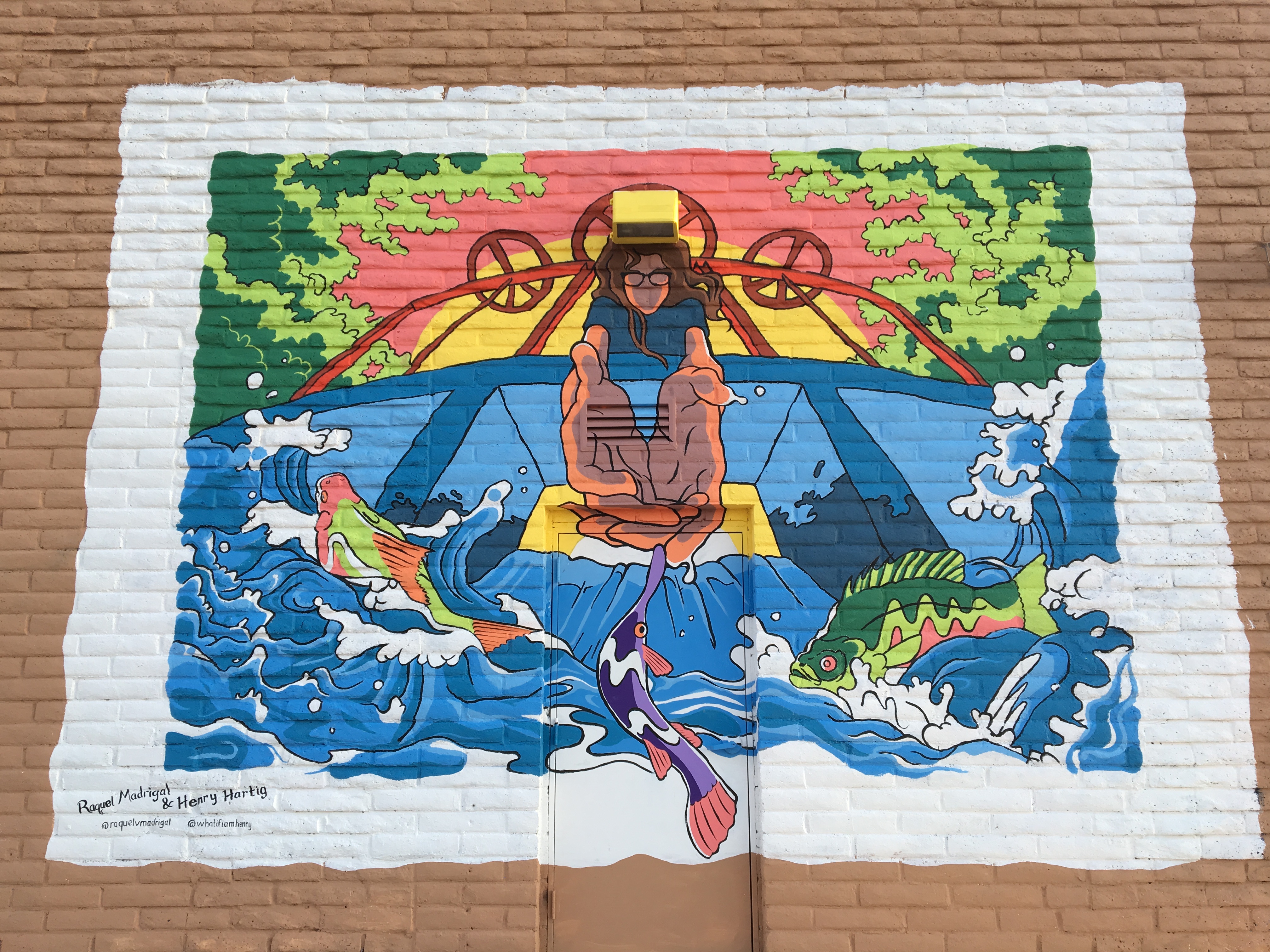 Mural of a person assisting endangered local fish over an acequia dam